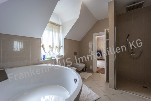 Geräumiges Badezimmer mit Badewanne, Dusche und hellen Fenster.