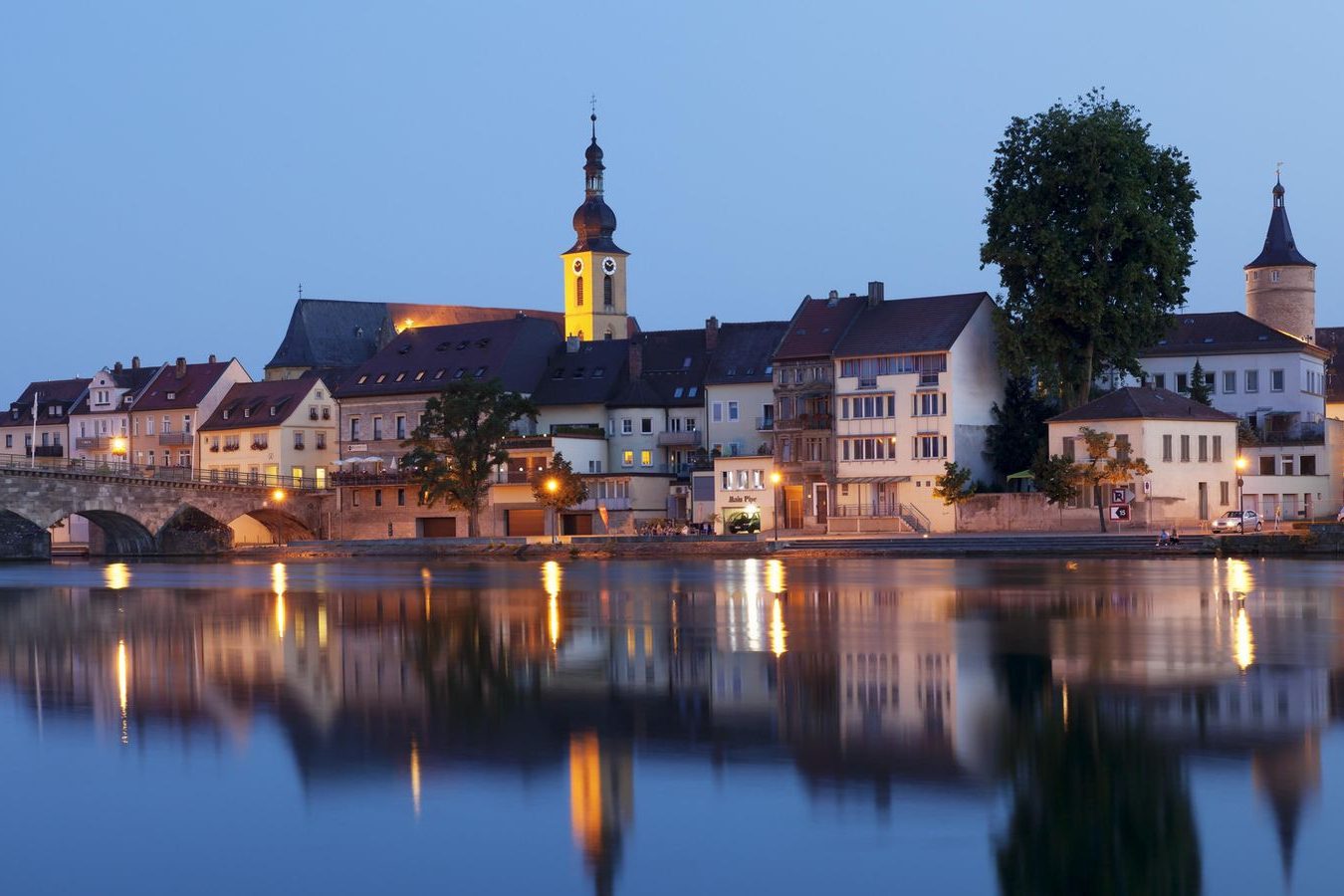 Modern Wohnzimmer mit weißen und schwarzen Möbeln, großen Fenstern und Pflanzen.