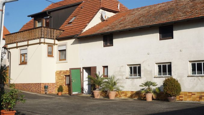 Ein älteres Gebäude mit einem roten Ziegeldach und Pflanzen in Töpfen im Vordergrund.