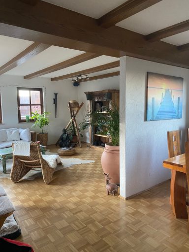 Heller Wohnraum mit Holzstuhl, Pflanzen und Gemälde an der Wand.