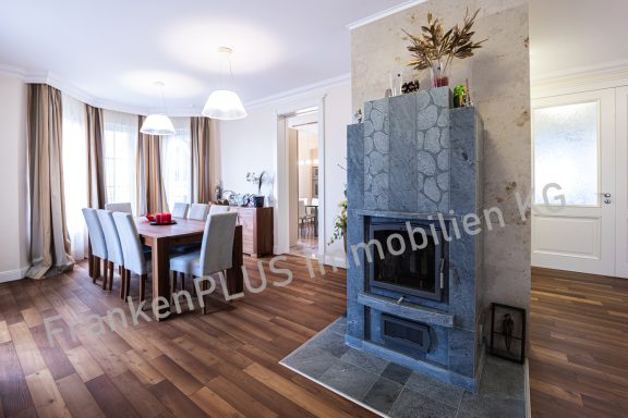 Geräumiges Wohnzimmer mit Essbereich, Kamin und Holzfußboden.