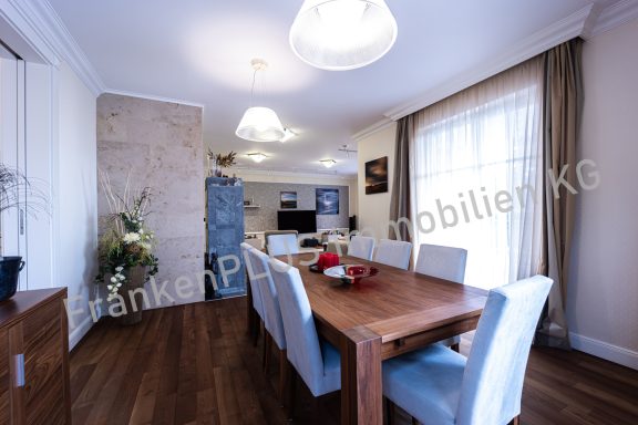 Helles, modernes Esszimmer mit großem Holztisch und eleganten Stühlen.