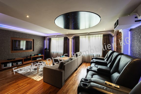 Modern Wohnzimmer mit großem Sofa, Kinostühlen und stimmungsvollem Lichtdesign.