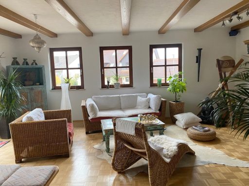 Helles Wohnzimmer mit Rattanmöbeln, Pflanzen und Holzdecke. Gemütliche Atmosphäre.