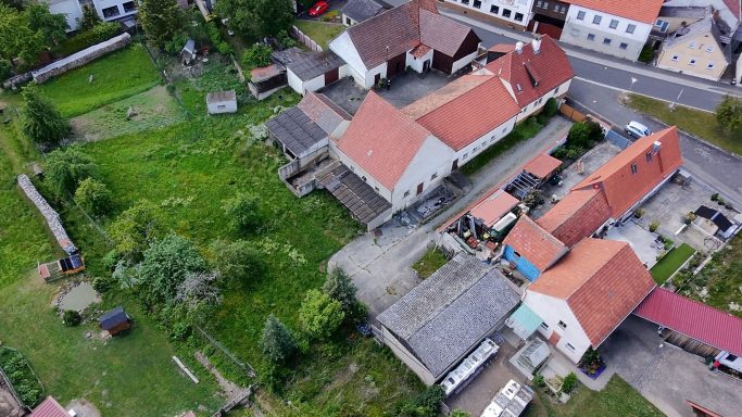 Luftaufnahme einer ländlichen Umgebung mit mehreren Gebäuden und einem grünen Garten.